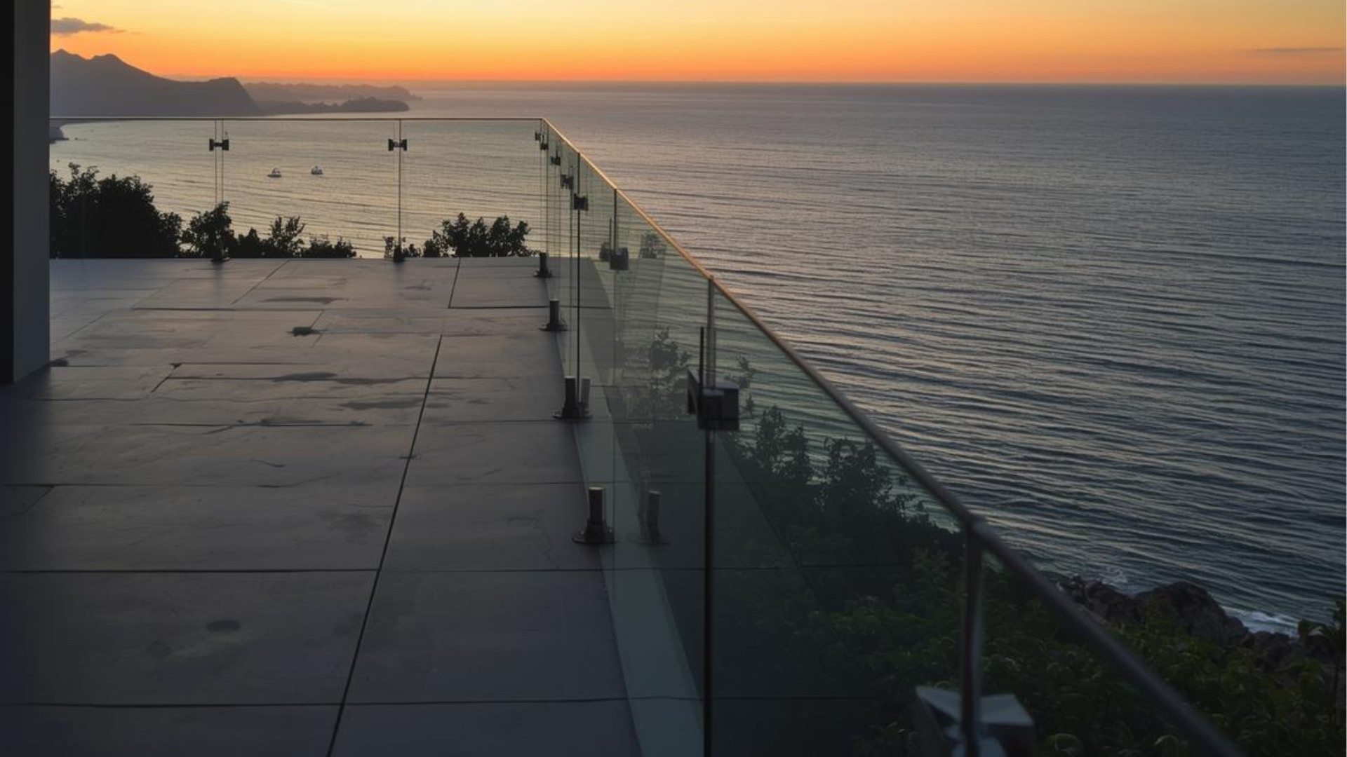 Terraza moderna con barandilla de cristal y vistas al mar al atardecer